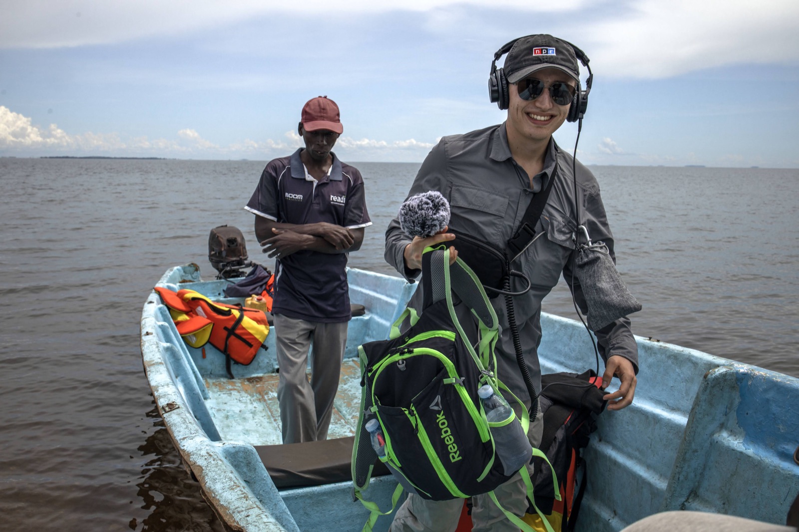 Michal Ruprecht holding a microphone and wearing headphones on a boat on Lake Victoria in Uganda